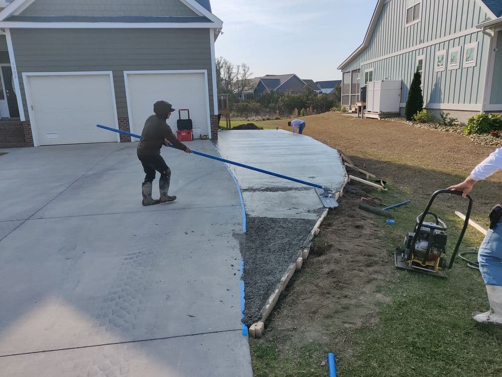 Workers pouring concrete for a new driveway installation at a residential property.