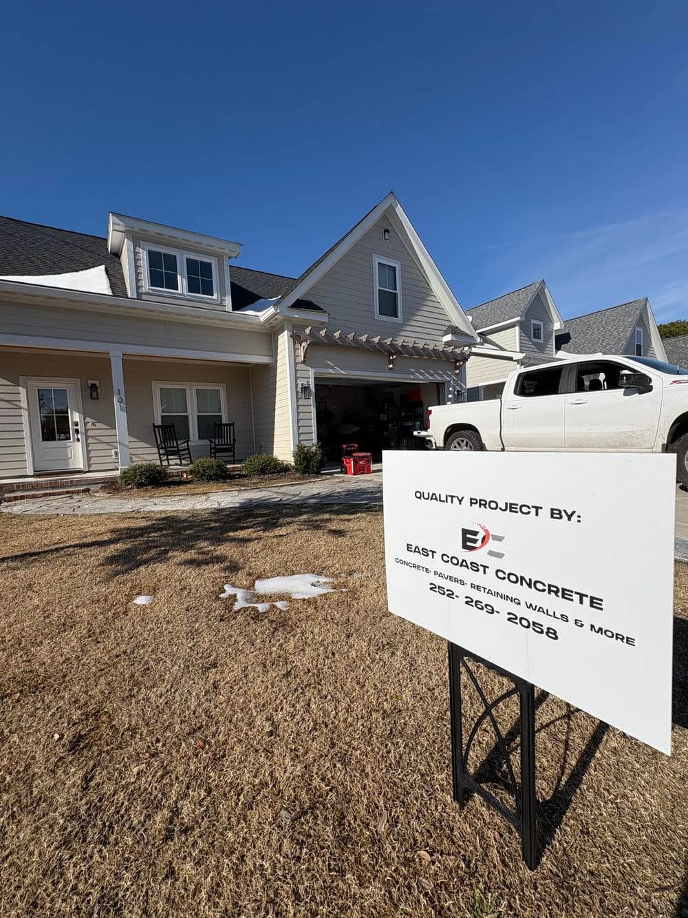 East Coast Concrete project sign in front of a house with a truck and porch. Quality construction.