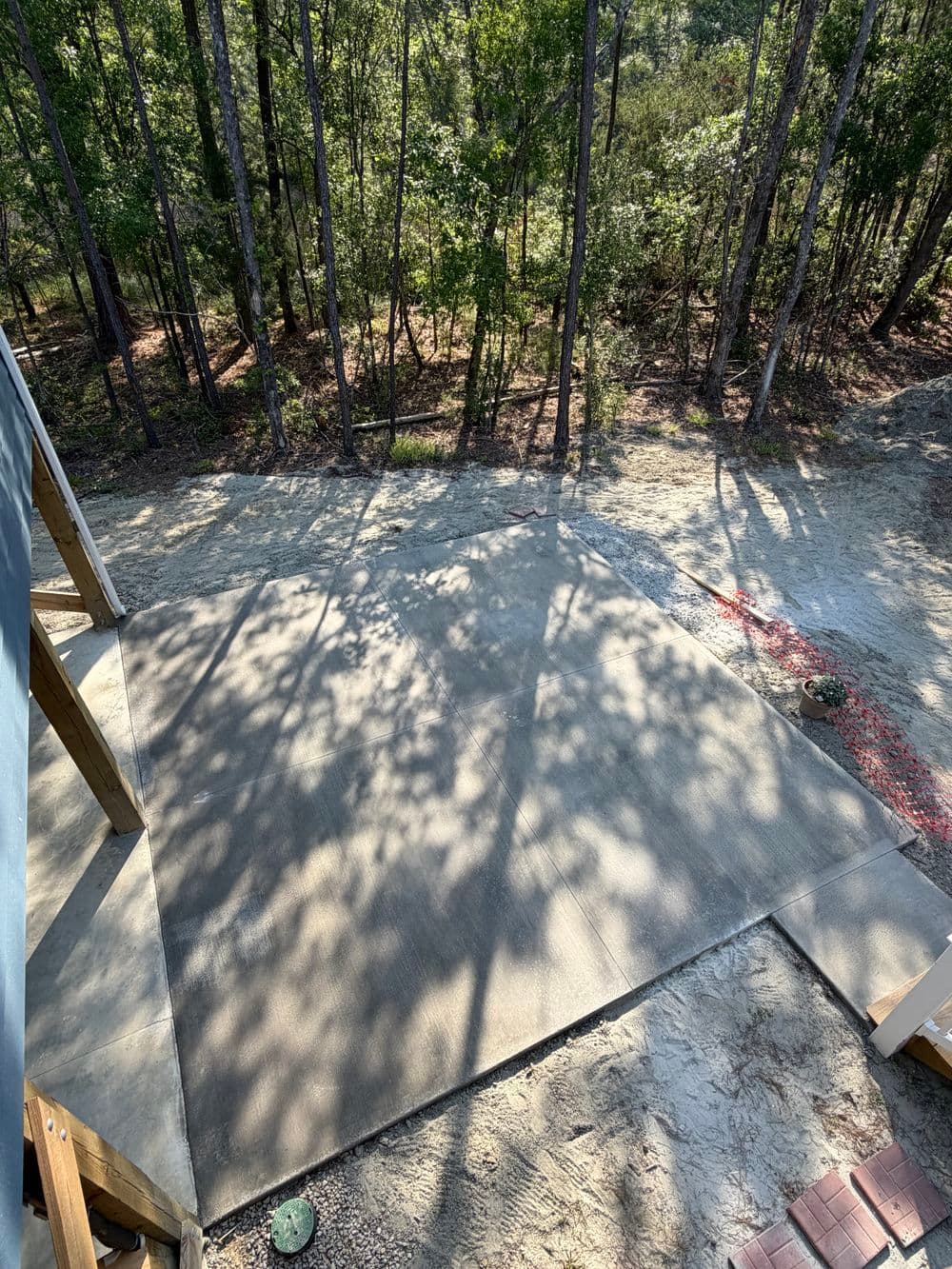 Concrete slab installation in wooded area, surrounded by trees and natural sunlight.