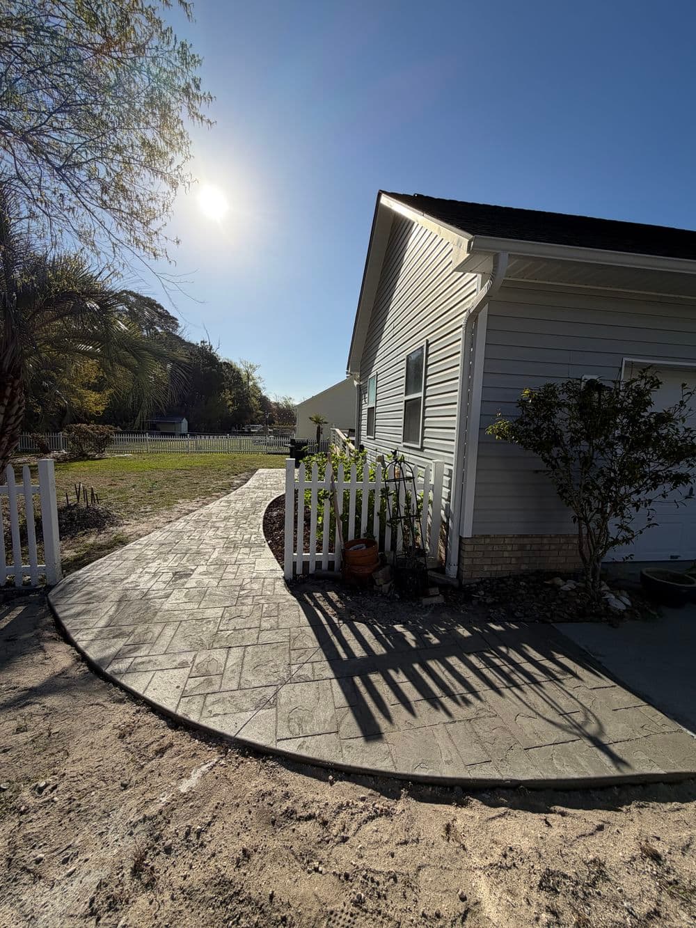 Pathway leading to a home with sunlit garden and detailed stonework.
