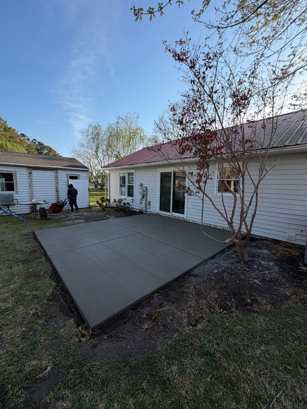 Freshly poured concrete patio beside a house, enhancing outdoor living space.