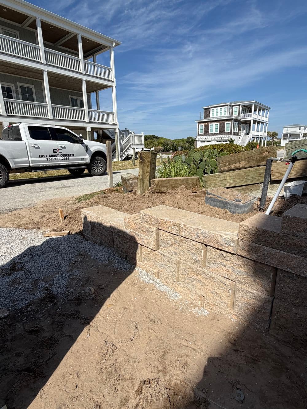 Construction site featuring stone steps and a parked truck outside beach houses.