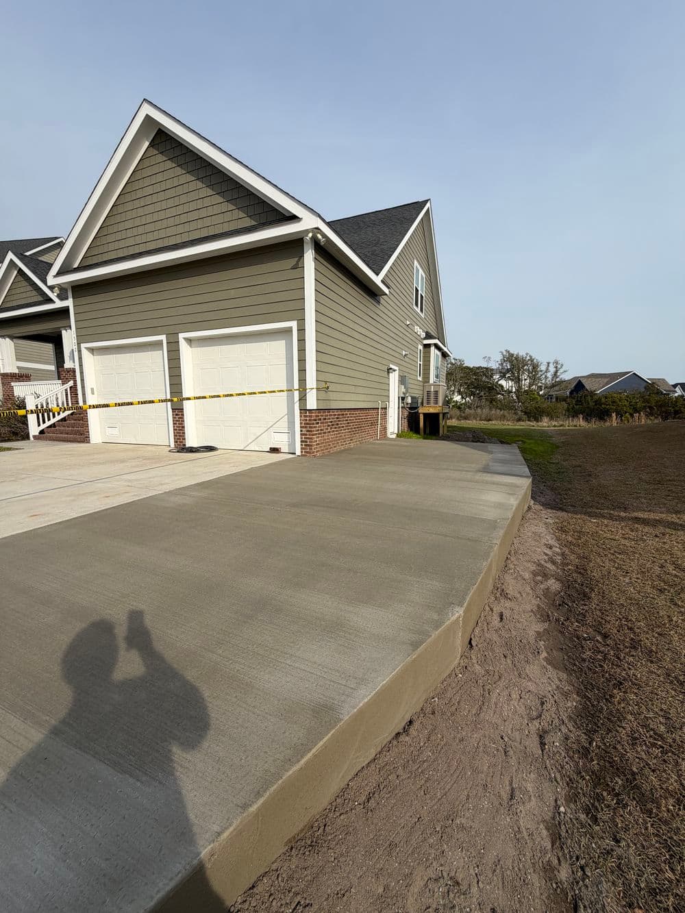 Newly poured concrete driveway alongside a modern home with a two-car garage.